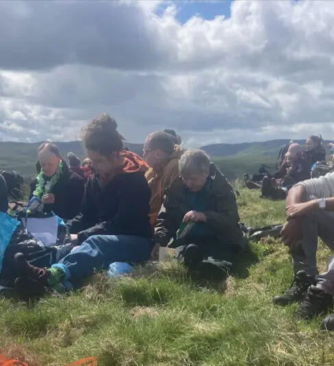 Lots of people enjoying a picnic at the top of a hill.